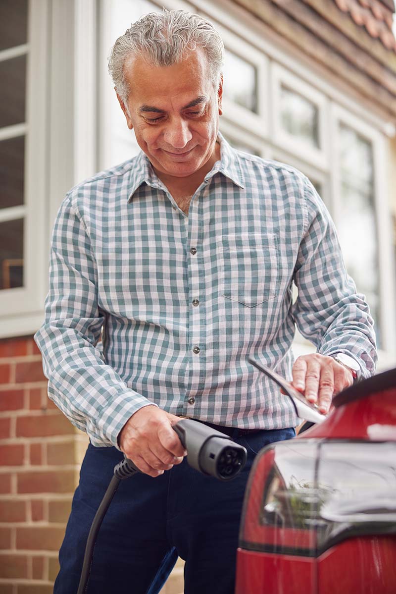 Elderly man putting his electric vehicle on charge